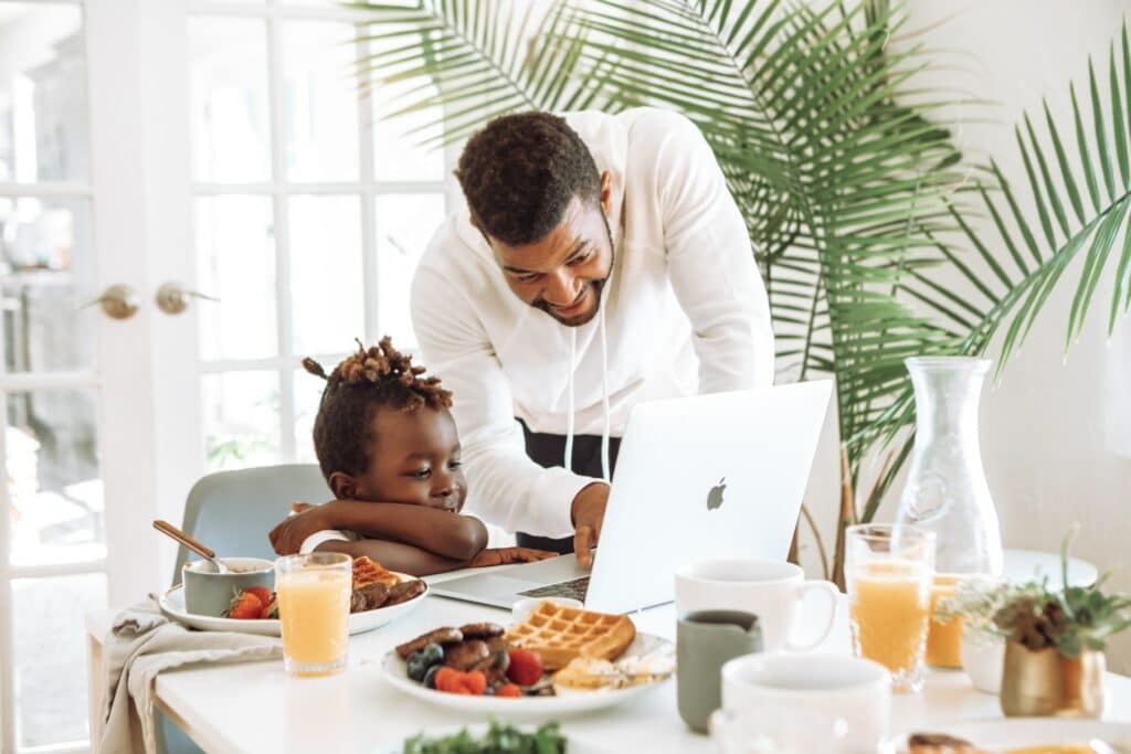 A father and child share time together over breakfast. Making time for yourself and others are an important part of the best work from home routine.