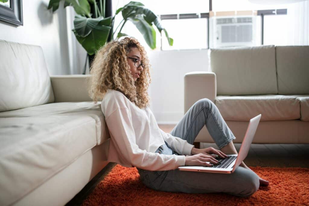 A person sitting on the floor using a laptop that is a part of online security.