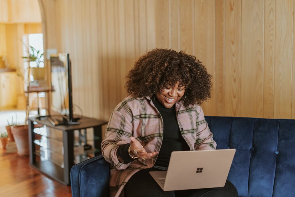 A person sat on a sofa talking to someone on a call using a laptop computer which would contain tools for remote work.